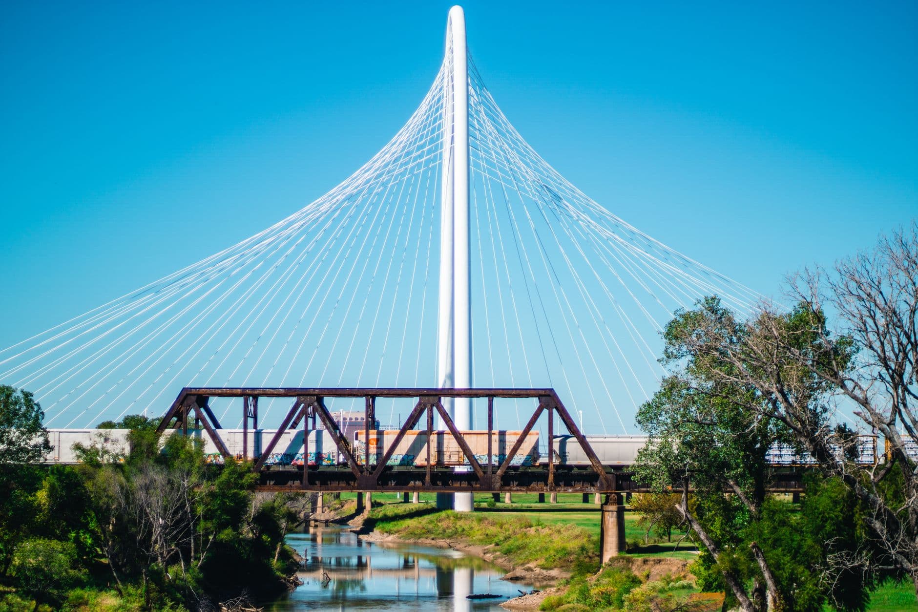 View of the Margaret Hunt Hill Bridge with a train passing underneath in Dallas, Texas.